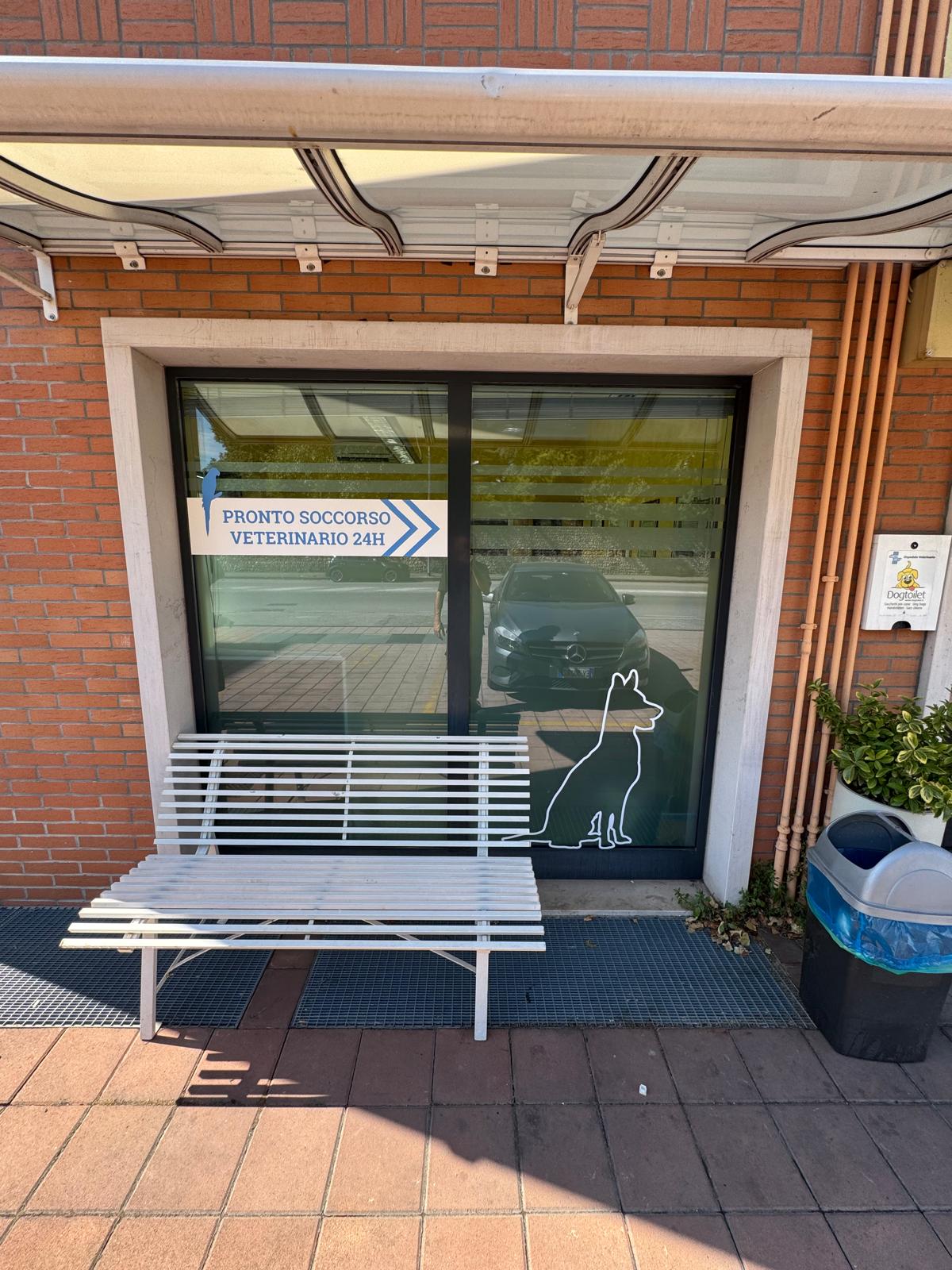 Ingresso del Pronto Soccorso Veterinario h24 a Verona presso l'Ospedale Santa Lucia, con insegna adesiva e panchina esterna per l'accoglienza delle emergenze.